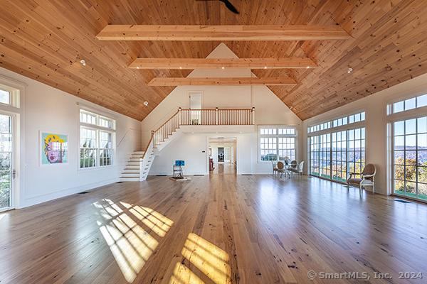 unfurnished living room with plenty of natural light, high vaulted ceiling, and wood-type flooring