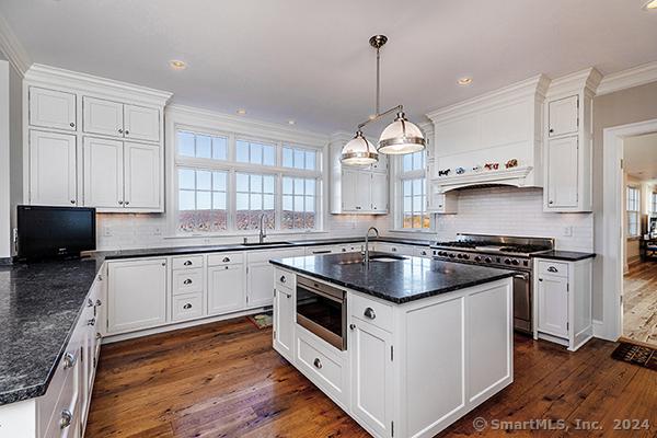 kitchen featuring dark hardwood / wood-style flooring, a center island with sink, white cabinets, and stainless steel appliances