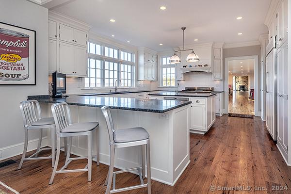 kitchen featuring backsplash, dark wood-type flooring, white cabinets, and hanging light fixtures