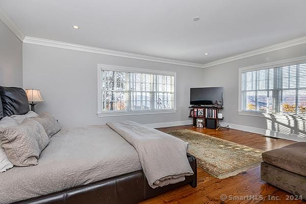 bedroom with wood-type flooring, crown molding, and multiple windows