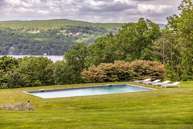 view of swimming pool with a lawn and a water view