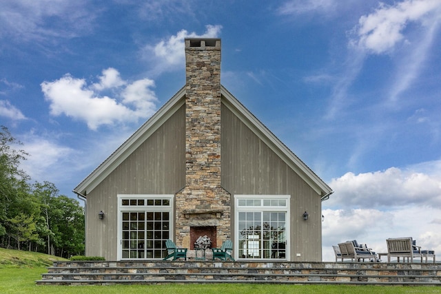 rear view of property featuring an outdoor stone fireplace