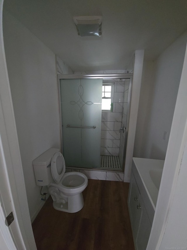 bathroom featuring toilet, vanity, a shower with door, and wood-type flooring