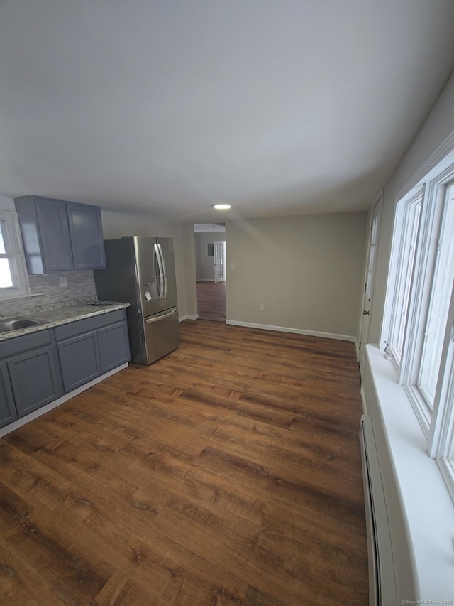 kitchen featuring tasteful backsplash, dark wood-type flooring, stainless steel refrigerator with ice dispenser, baseboard heating, and gray cabinets