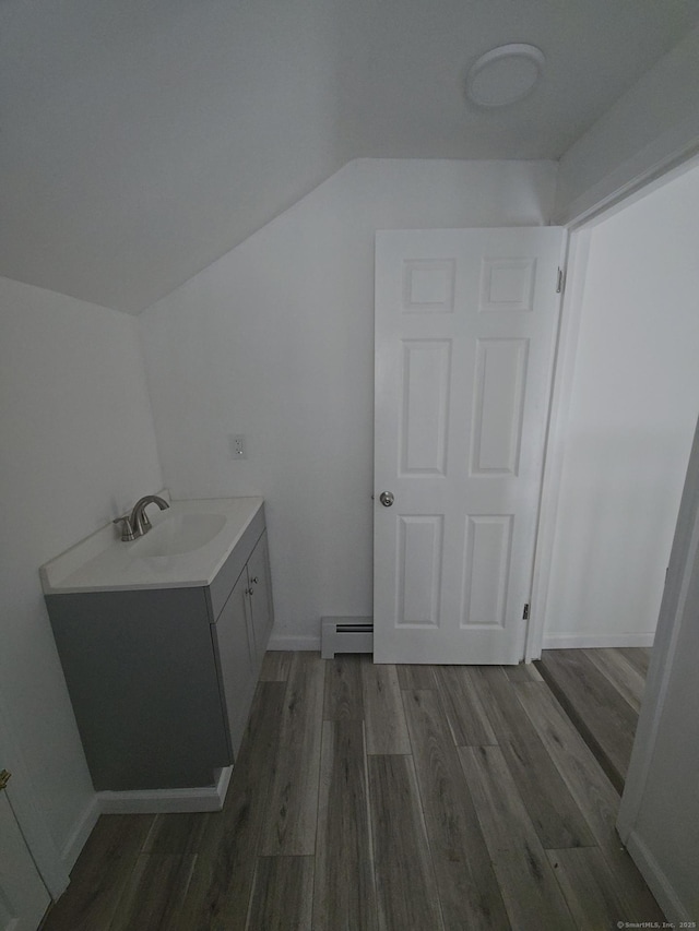 bathroom featuring hardwood / wood-style flooring, vanity, lofted ceiling, and baseboard heating