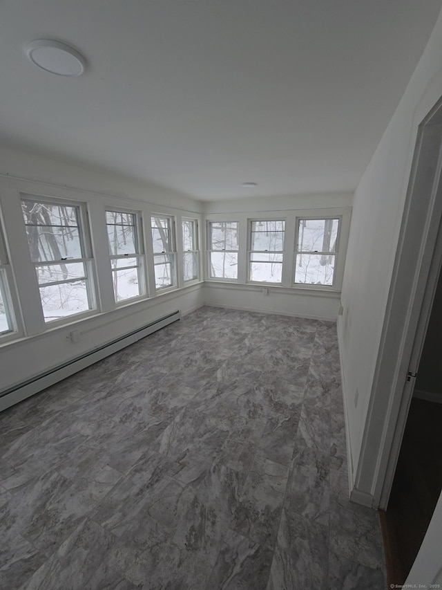 unfurnished sunroom featuring a baseboard heating unit and plenty of natural light