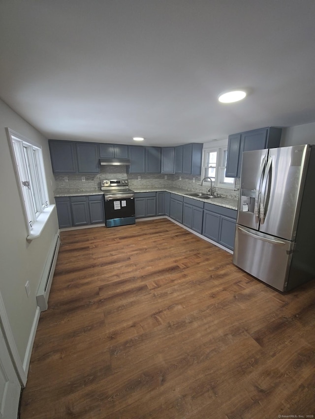 kitchen with appliances with stainless steel finishes, tasteful backsplash, baseboard heating, dark hardwood / wood-style flooring, and sink