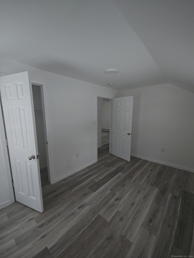 unfurnished bedroom featuring dark wood-type flooring and vaulted ceiling