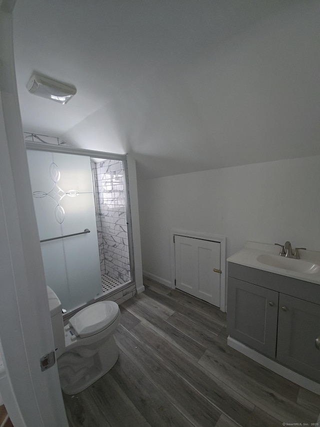 bathroom featuring toilet, lofted ceiling, walk in shower, hardwood / wood-style floors, and vanity