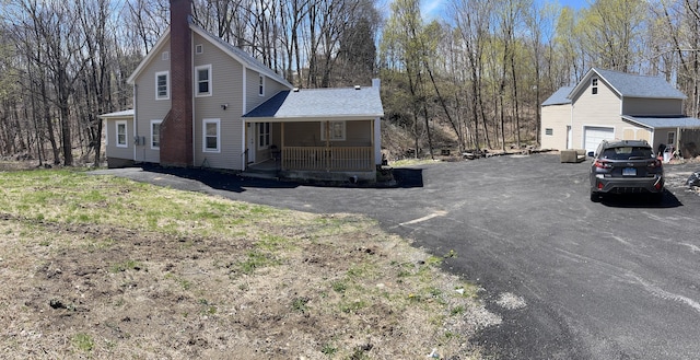 971 New Litchfield St, Torrington, CT 06790 - view of side of home with driveway, a chimney, a shingled roof, covered porch, and a garage