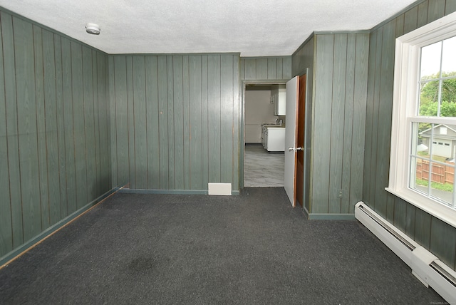 carpeted empty room featuring plenty of natural light, a textured ceiling, and a baseboard radiator