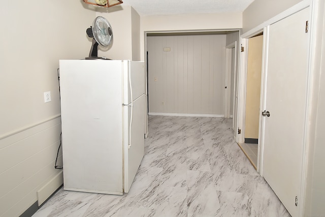 kitchen with white fridge, a textured ceiling, and light tile floors