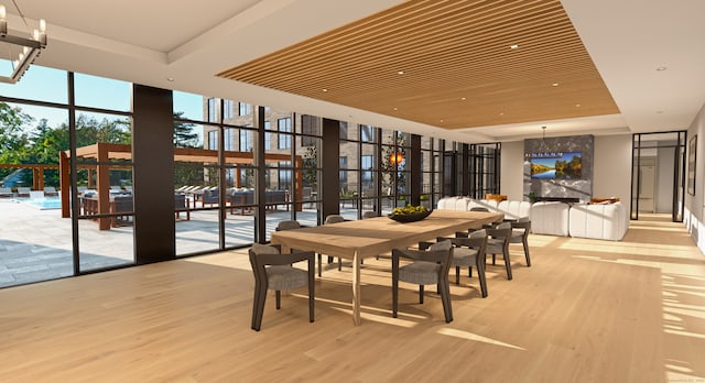 dining room featuring a tray ceiling, light hardwood / wood-style flooring, and a wall of windows