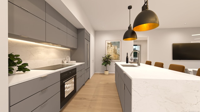 kitchen featuring light wood-type flooring, sink, black appliances, decorative light fixtures, and gray cabinets