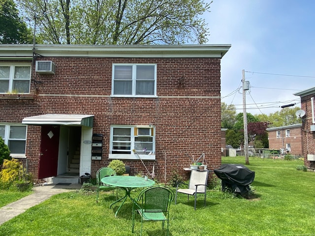 exterior space with a wall mounted air conditioner and a front yard