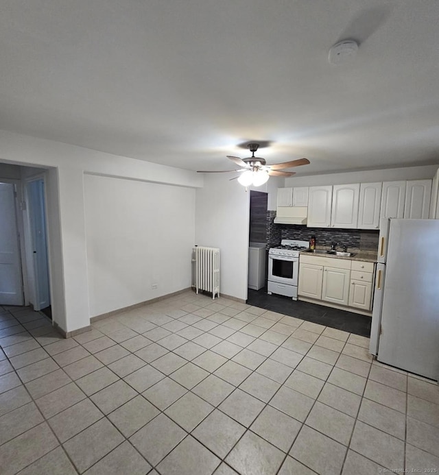 kitchen featuring radiator heating unit, white appliances, ceiling fan, decorative backsplash, and white cabinetry