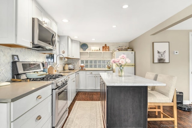 kitchen featuring a center island, dark hardwood / wood-style floors, white cabinetry, appliances with stainless steel finishes, and sink