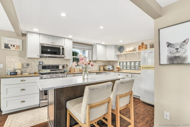 kitchen with stainless steel appliances, a center island, dark hardwood / wood-style flooring, and white cabinetry