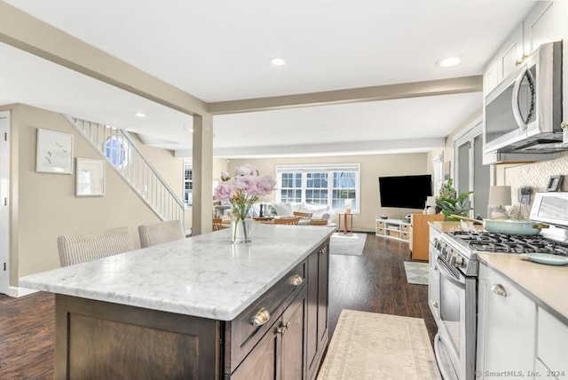 kitchen with white cabinetry, a kitchen bar, dark brown cabinetry, dark hardwood / wood-style flooring, and gas range