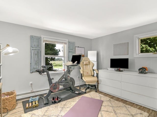 workout room with light hardwood / wood-style floors and a baseboard heating unit