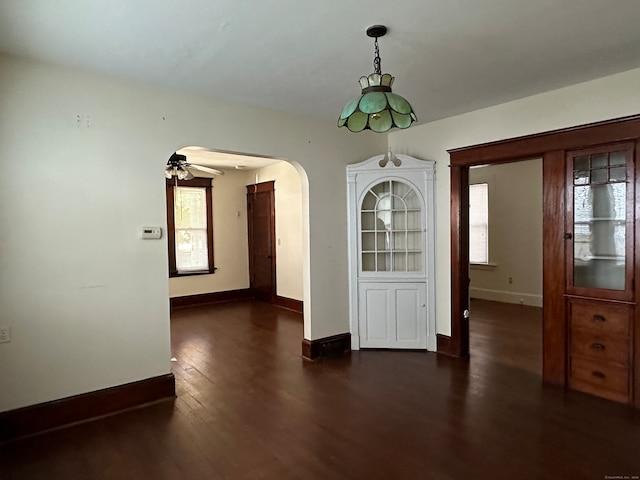 unfurnished dining area with ceiling fan, dark hardwood / wood-style floors, and plenty of natural light