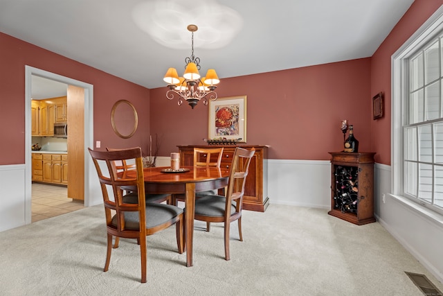 dining area featuring light carpet and a chandelier