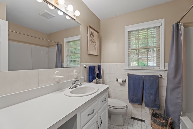 full bathroom featuring vanity, shower / bathtub combination with curtain, tile patterned floors, tile walls, and toilet