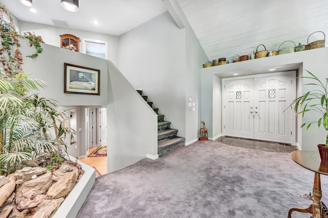 foyer with carpet and high vaulted ceiling