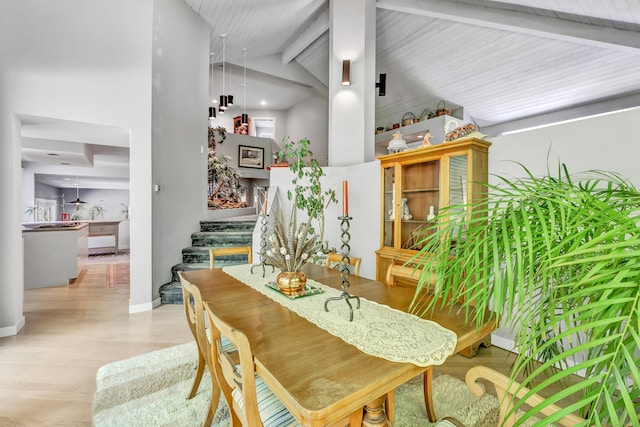 dining room with light wood-type flooring and vaulted ceiling with beams