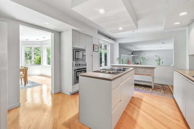 kitchen featuring light hardwood / wood-style flooring, a kitchen island, stainless steel gas stovetop, and a healthy amount of sunlight