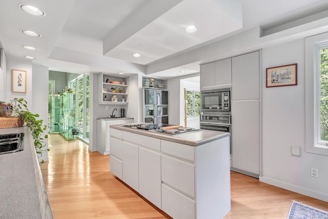 kitchen with white cabinets, light wood-type flooring, a center island, and black appliances