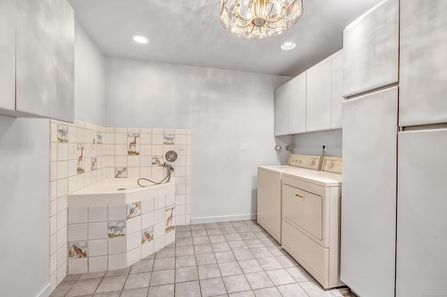 washroom featuring washing machine and dryer, light tile patterned floors, and an inviting chandelier