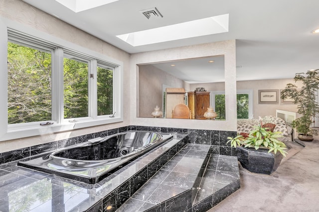 bathroom featuring a skylight and a relaxing tiled tub