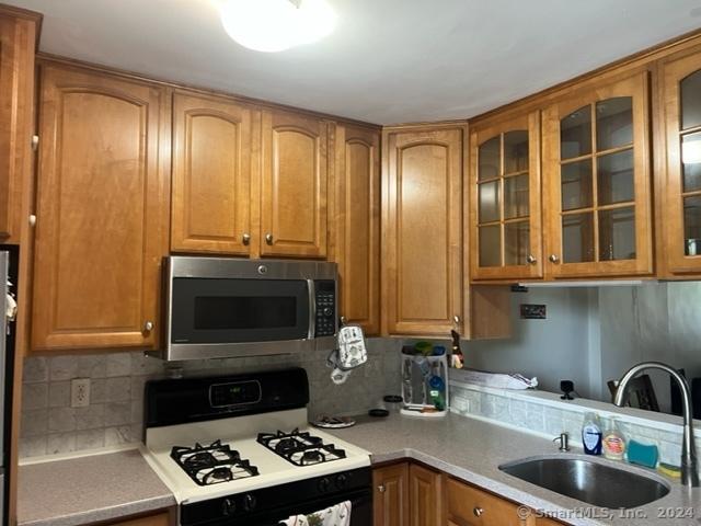 kitchen featuring backsplash, white gas stove, and sink