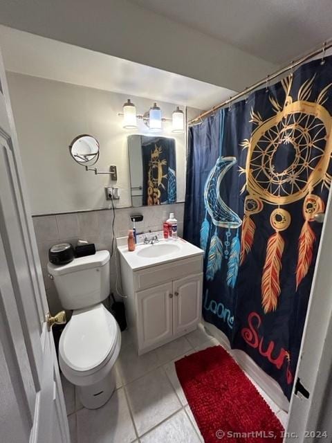 bathroom with a shower with shower curtain, tile patterned floors, vanity, tile walls, and toilet