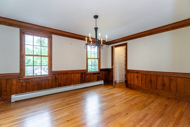 unfurnished room featuring light hardwood / wood-style floors, ornamental molding, baseboard heating, and a chandelier