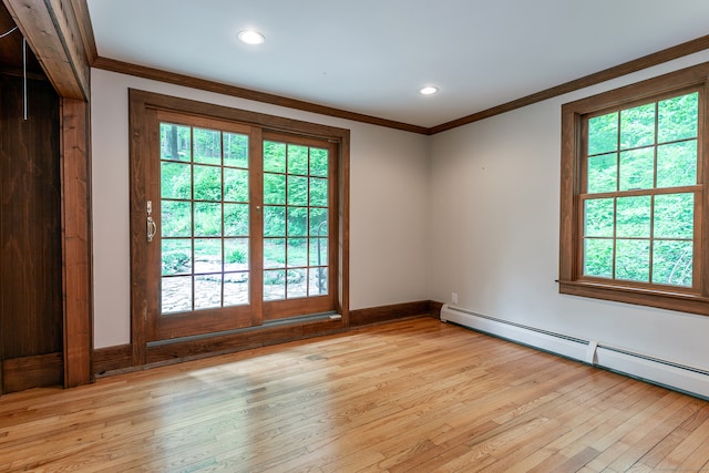 spare room featuring light hardwood / wood-style floors, baseboard heating, and plenty of natural light