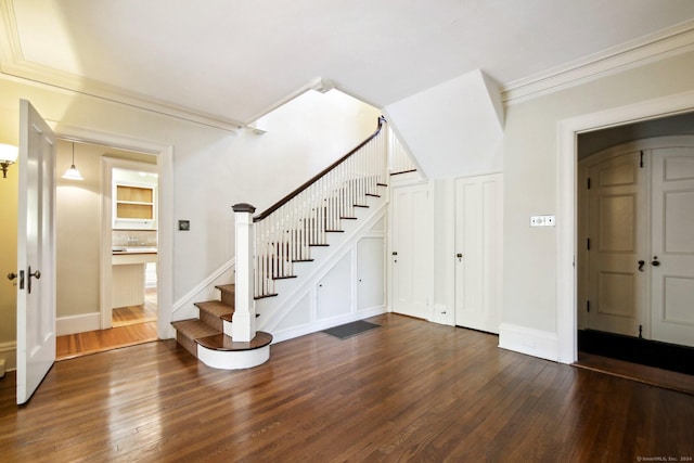 foyer entrance featuring dark wood-type flooring and crown molding