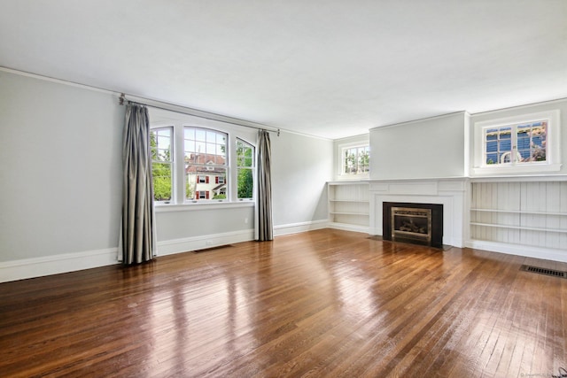 unfurnished living room featuring dark hardwood / wood-style flooring, a healthy amount of sunlight, and built in shelves