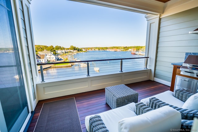 balcony with an outdoor living space, a water view, and a grill