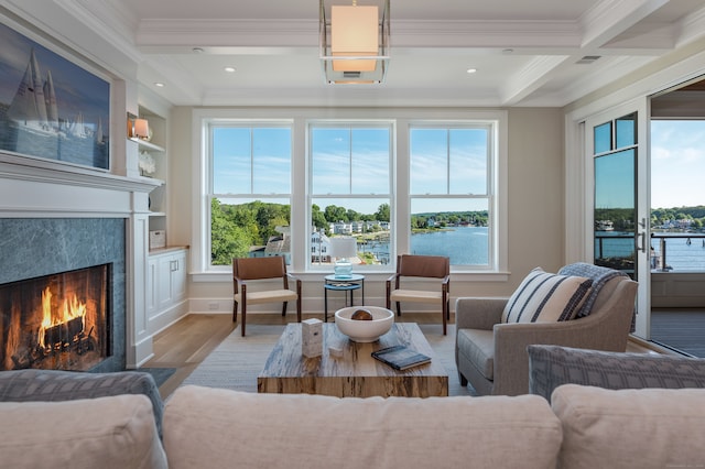 living room with light hardwood / wood-style flooring, a water view, beamed ceiling, a fireplace, and coffered ceiling