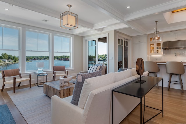 living room featuring beamed ceiling, coffered ceiling, light hardwood / wood-style flooring, and a water view