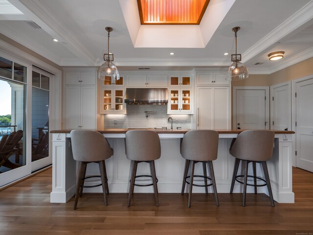 kitchen with dark hardwood / wood-style flooring, wall chimney exhaust hood, and pendant lighting