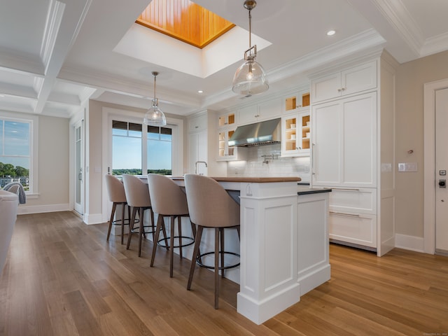 kitchen featuring coffered ceiling, backsplash, hardwood / wood-style floors, white cabinetry, and beamed ceiling