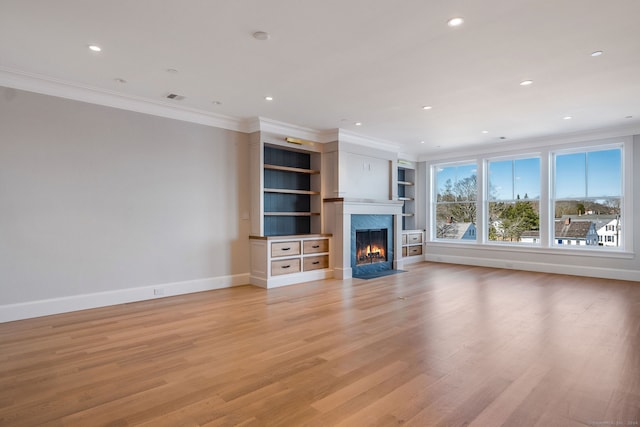 unfurnished living room featuring built in shelves, a high end fireplace, crown molding, and light hardwood / wood-style flooring