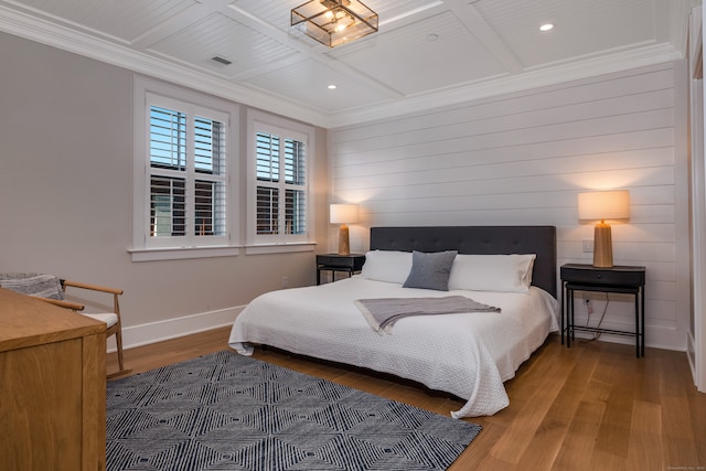 bedroom with coffered ceiling, crown molding, and hardwood / wood-style flooring