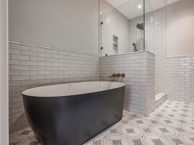 bathroom featuring tile floors, shower with separate bathtub, and tile walls