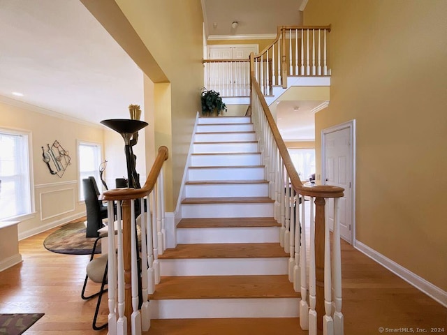 staircase with hardwood / wood-style floors and ornamental molding