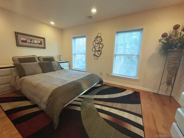 bedroom with light hardwood / wood-style floors and multiple windows