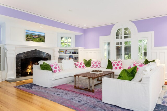 living room featuring wood-type flooring, ornamental molding, and a fireplace